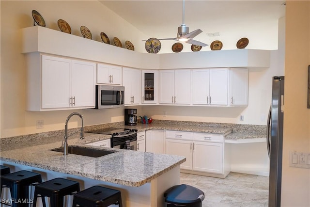 kitchen with light stone counters, stainless steel appliances, glass insert cabinets, white cabinets, and a peninsula