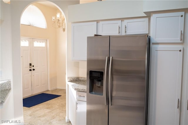 kitchen featuring white cabinetry, stainless steel refrigerator with ice dispenser, and light stone countertops