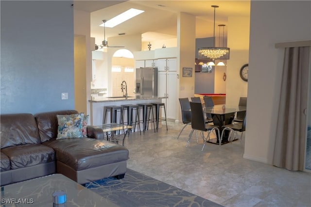 living area featuring high vaulted ceiling, baseboards, and an inviting chandelier