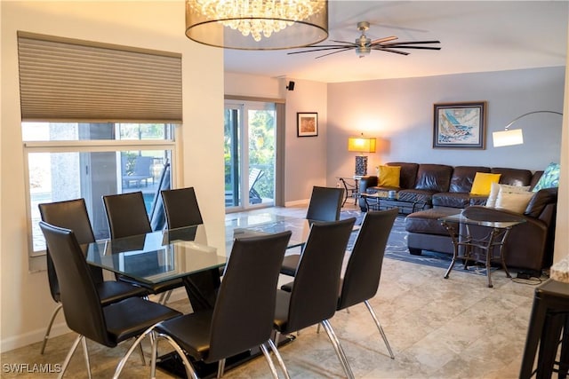 dining space with baseboards and ceiling fan with notable chandelier