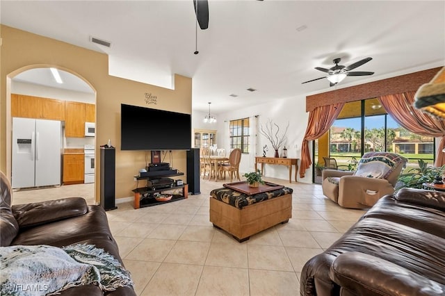 living area with light tile patterned floors, visible vents, a wealth of natural light, and a ceiling fan