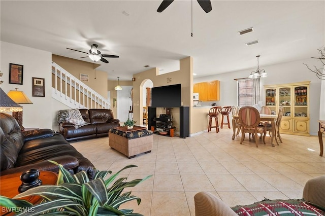 living area with stairs, ceiling fan with notable chandelier, light tile patterned flooring, and visible vents