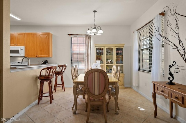 dining area with a chandelier, light tile patterned floors, and baseboards