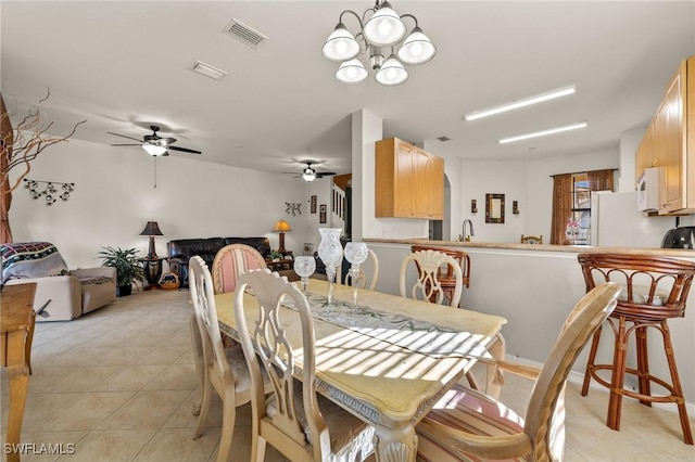 dining room featuring ceiling fan with notable chandelier, visible vents, and light tile patterned floors