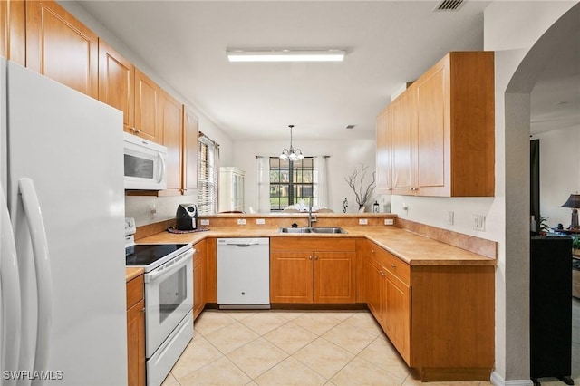 kitchen with light tile patterned floors, light countertops, a sink, a chandelier, and white appliances