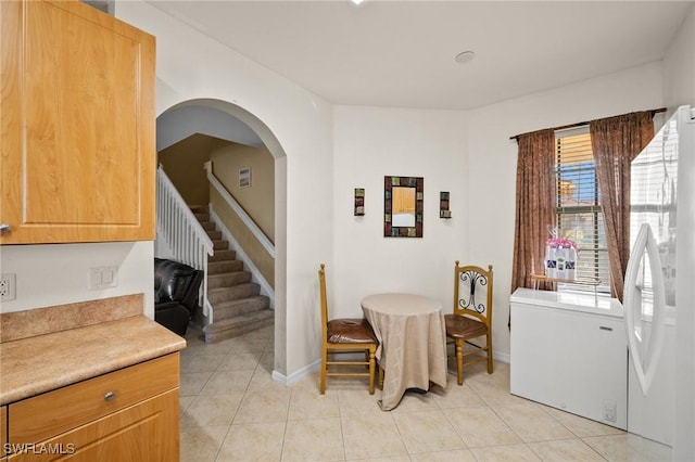 dining area featuring baseboards, stairway, arched walkways, and light tile patterned flooring