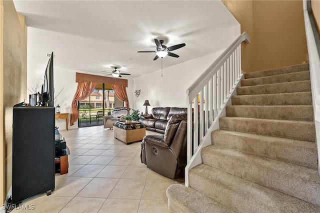 living room featuring light tile patterned floors, ceiling fan, and stairway