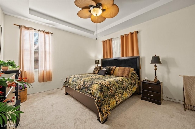 bedroom featuring carpet floors, a raised ceiling, and a ceiling fan