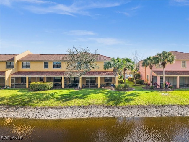 rear view of house featuring a water view, stucco siding, and a yard