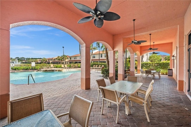 view of patio / terrace with a community pool, a ceiling fan, and outdoor dining space