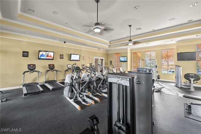 exercise room with baseboards, a tray ceiling, and crown molding