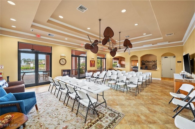 interior space with visible vents, arched walkways, a ceiling fan, a tray ceiling, and french doors