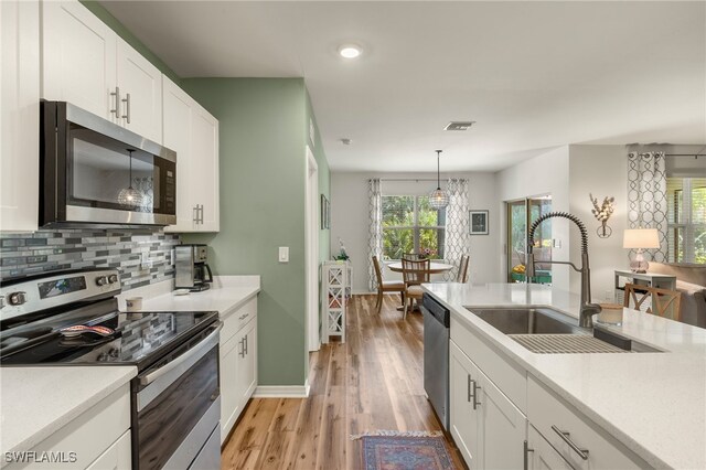 18512 Marlin Kite Ln, North Fort Myers, FL 33917 - kitchen with hanging light fixtures, white cabinetry, appliances with stainless steel finishes, and light countertops