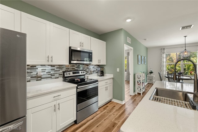 18512 Marlin Kite Ln, North Fort Myers, FL 33917 - kitchen with tasteful backsplash, appliances with stainless steel finishes, hanging light fixtures, white cabinetry, and a sink