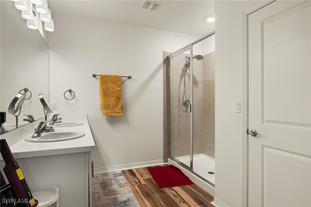 18512 Marlin Kite Ln, North Fort Myers, FL 33917 - full bath featuring wood finished floors, a sink, visible vents, double vanity, and a stall shower