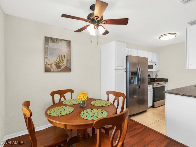 dining space featuring light wood finished floors, ceiling fan, visible vents, and baseboards