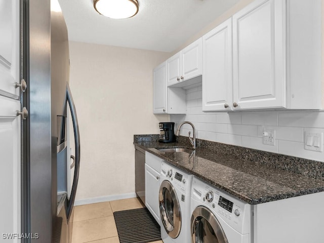 clothes washing area with light tile patterned floors, laundry area, baseboards, independent washer and dryer, and a sink