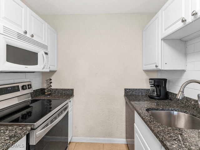 kitchen with stainless steel electric range oven, decorative backsplash, white microwave, white cabinets, and a sink