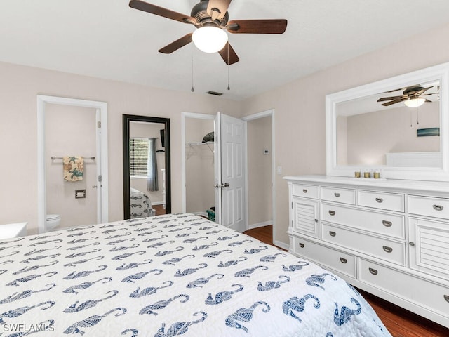 bedroom featuring dark wood-style flooring, a closet, visible vents, a spacious closet, and a ceiling fan