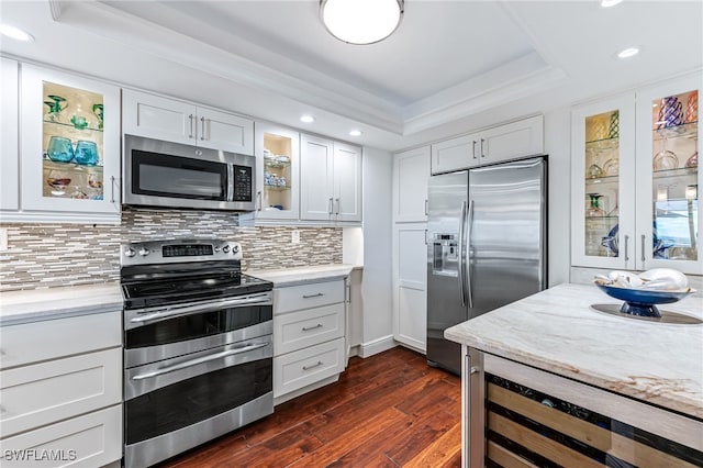 kitchen with beverage cooler, dark wood-type flooring, appliances with stainless steel finishes, decorative backsplash, and a tray ceiling