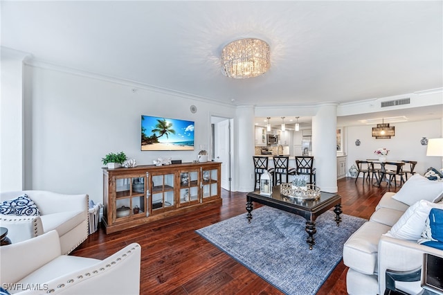 living room featuring hardwood / wood-style flooring, a notable chandelier, visible vents, and crown molding