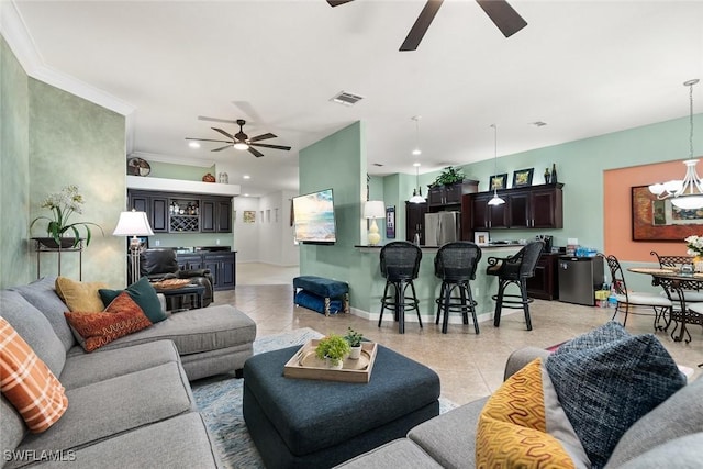 living room featuring light tile patterned floors, ceiling fan with notable chandelier, visible vents, baseboards, and crown molding