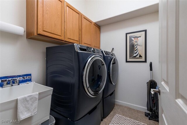 laundry room featuring light colored carpet, cabinet space, washing machine and dryer, a sink, and baseboards