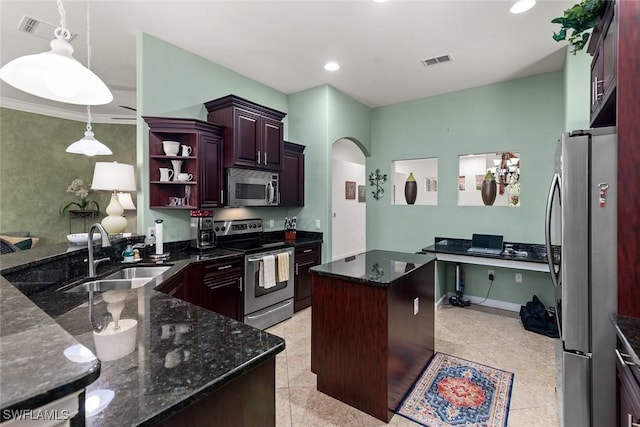 kitchen with a center island, arched walkways, stainless steel appliances, a sink, and dark stone countertops