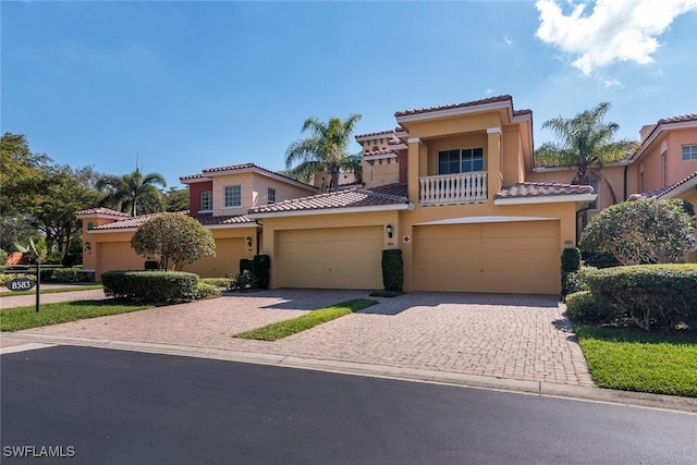 mediterranean / spanish-style home with decorative driveway, a tile roof, and stucco siding