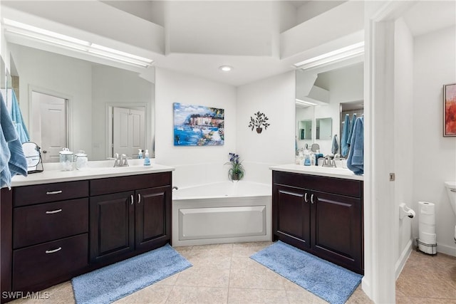 full bathroom featuring a garden tub, two vanities, a sink, and tile patterned floors