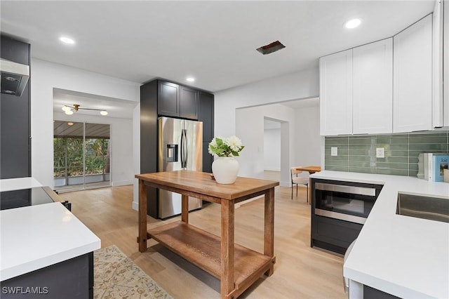 kitchen with light wood-style flooring, decorative backsplash, stainless steel appliances, and light countertops