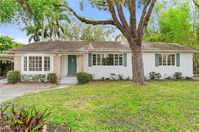 single story home with concrete driveway, an attached carport, a front yard, and stucco siding