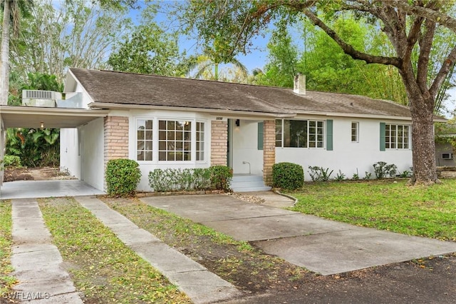 ranch-style home with a chimney, stucco siding, a shingled roof, an attached carport, and a front lawn