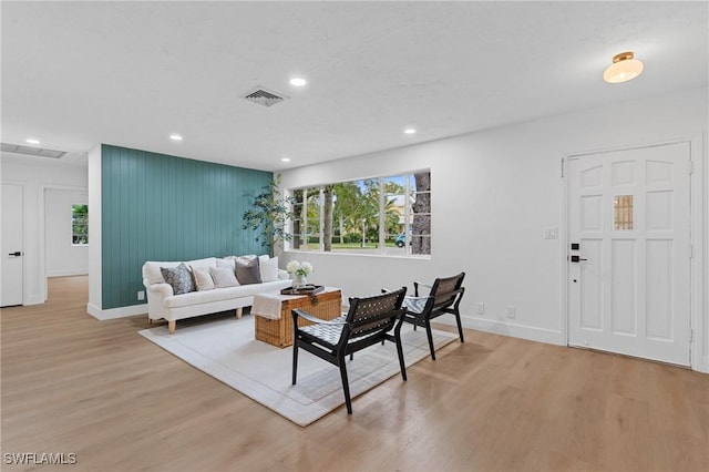 living area featuring baseboards, light wood-style flooring, visible vents, and recessed lighting