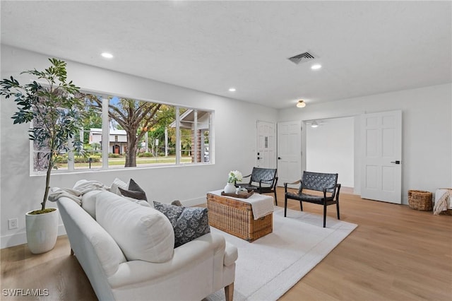 living room featuring baseboards, light wood-type flooring, visible vents, and recessed lighting