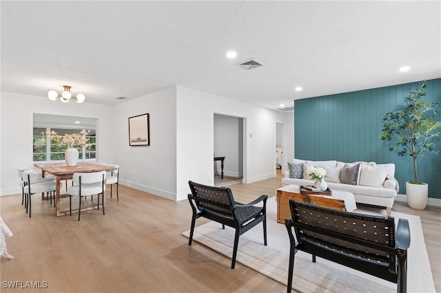 living area featuring light wood-style floors, visible vents, and an inviting chandelier