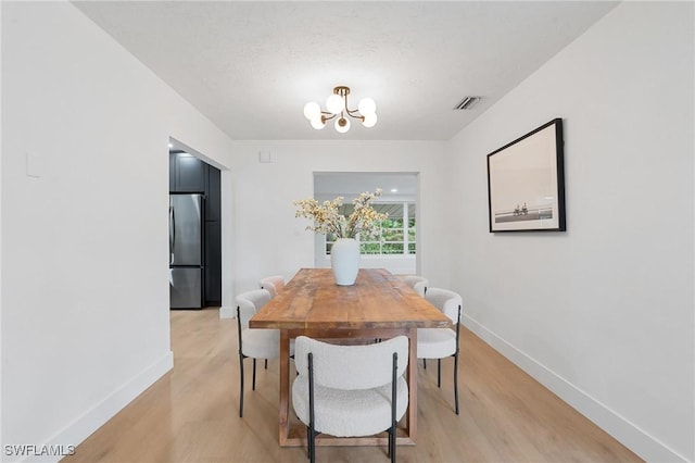 dining area featuring baseboards, light wood-style flooring, visible vents, and an inviting chandelier