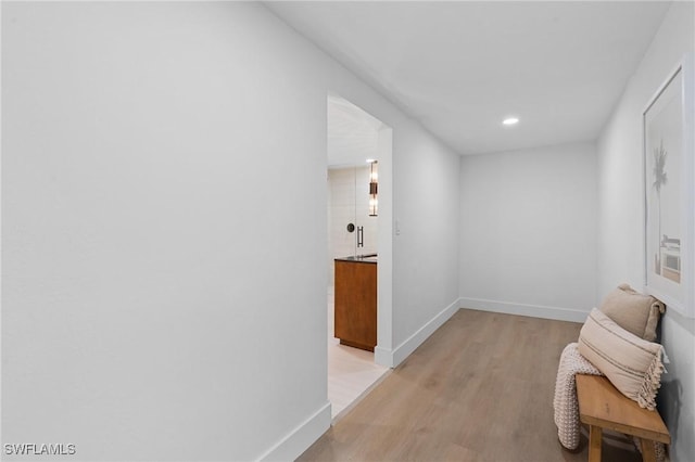 hall with baseboards, recessed lighting, and light wood-style floors