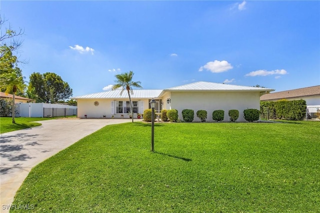 rear view of property featuring metal roof, fence, a yard, driveway, and stucco siding