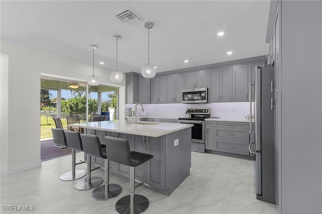 kitchen with tasteful backsplash, visible vents, gray cabinets, stainless steel appliances, and a sink