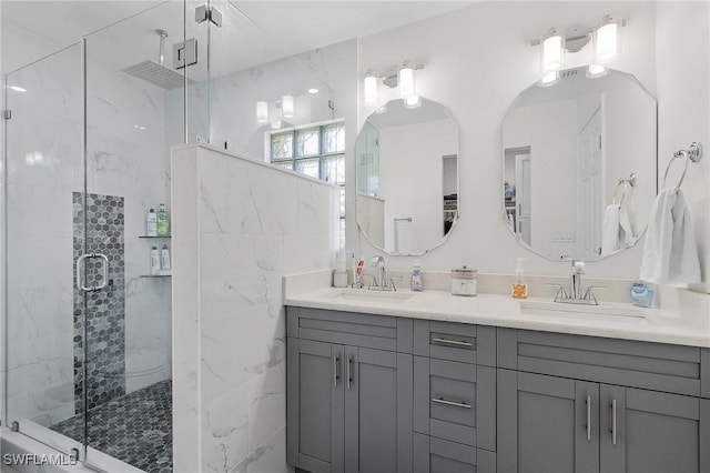 bathroom with double vanity, a sink, and a marble finish shower