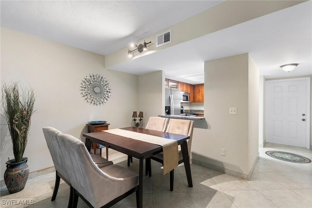 dining area featuring baseboards, visible vents, and light tile patterned flooring