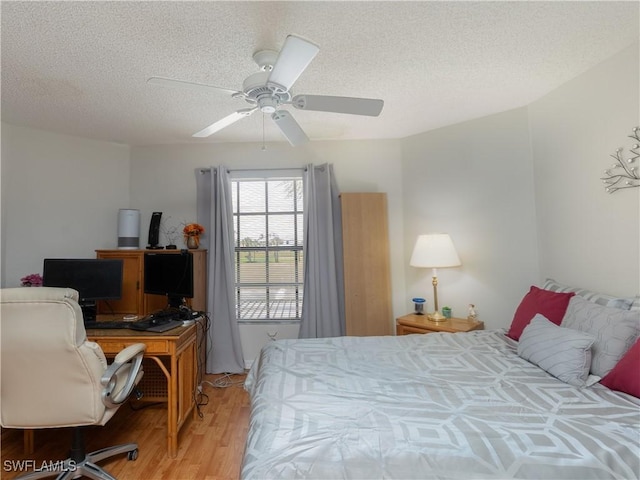 bedroom with light wood-style floors, ceiling fan, and a textured ceiling