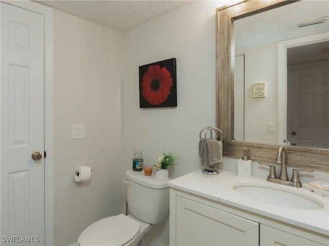 bathroom featuring toilet, visible vents, a textured ceiling, and vanity