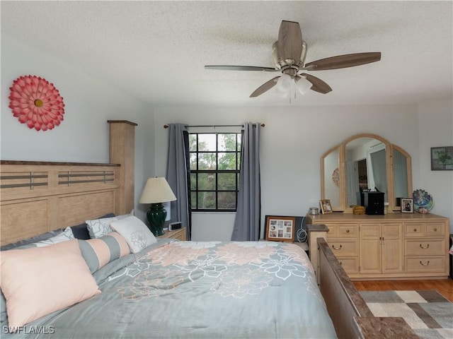 bedroom featuring light wood finished floors, a ceiling fan, and a textured ceiling