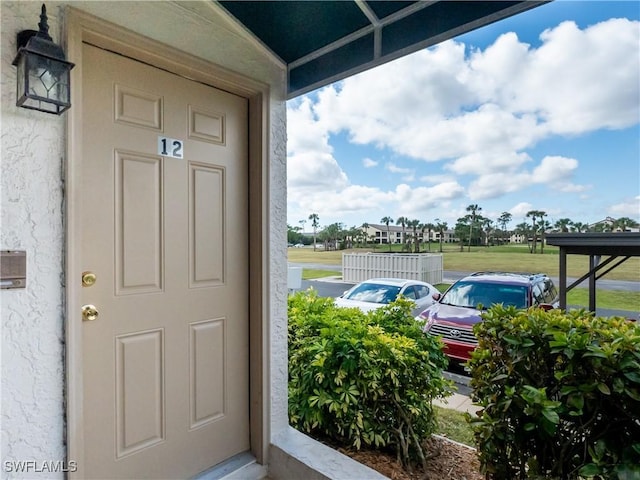 view of exterior entry with a lawn and stucco siding