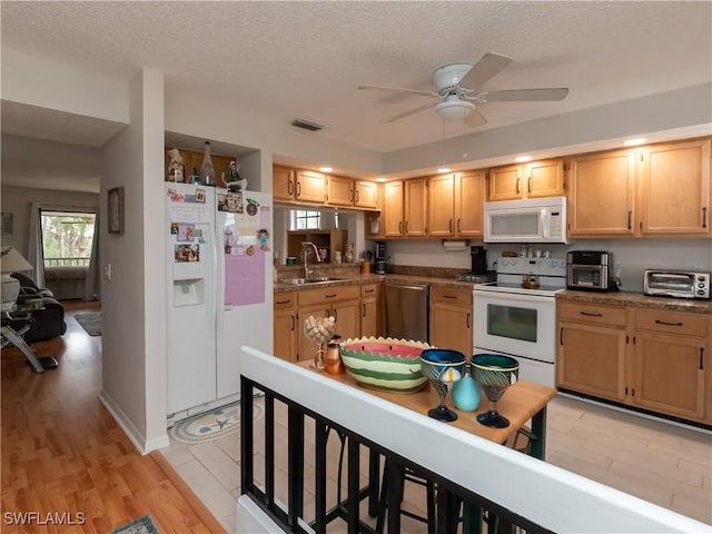 kitchen with white appliances, visible vents, light wood-style flooring, a textured ceiling, and a sink