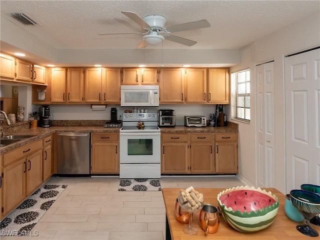 kitchen featuring a textured ceiling, white appliances, a sink, visible vents, and a ceiling fan