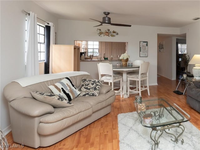 living room with ceiling fan, wood finished floors, visible vents, and baseboards