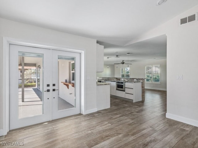 kitchen with visible vents, wood finished floors, french doors, a peninsula, and white cabinets